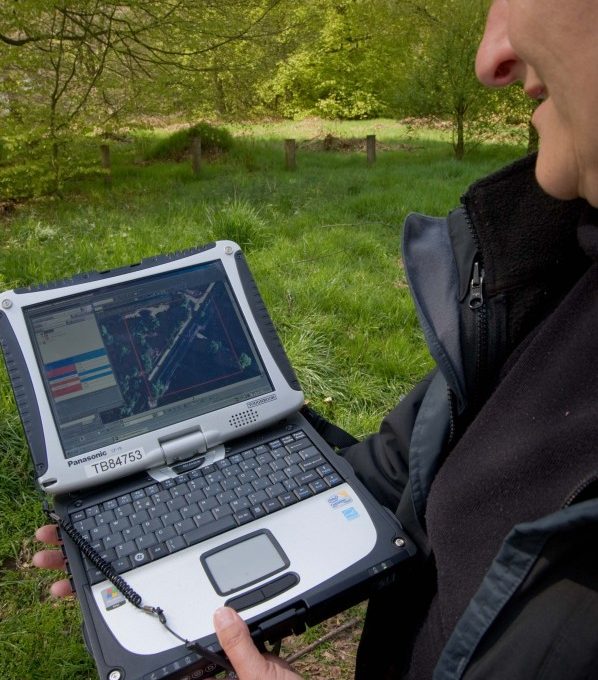 Person looking at computer in forest setting
