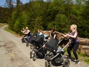 A number of mothers with buggies doing some sort of fitness activity