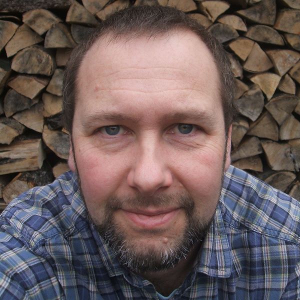 Image of Peter van-Velzen in front of a stack of firewood.