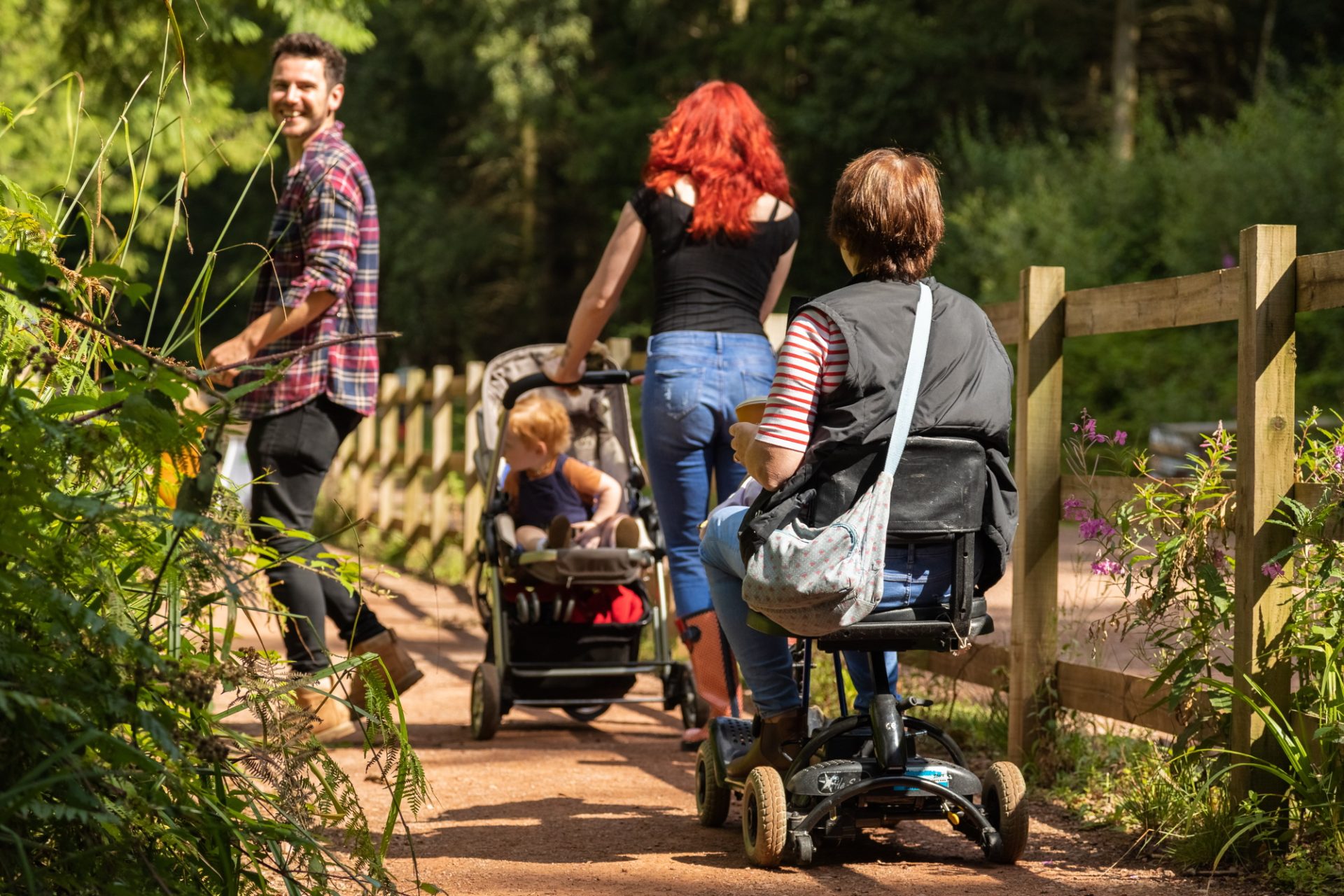 A family walk in a woodland. One of the people in the photograph uses a mobility device.