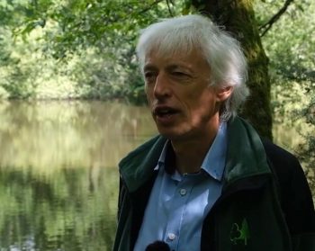 A photograph of Tom Nisbet with riparian woodland in the background.