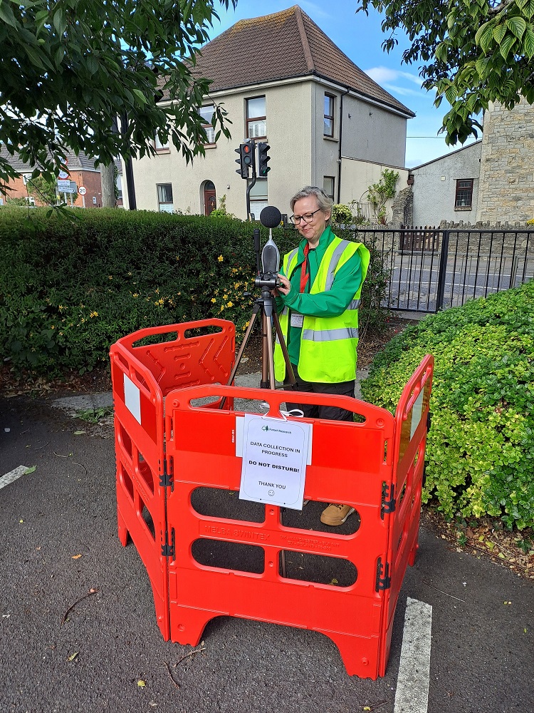 Scientist deploying noise sensor at road-side site