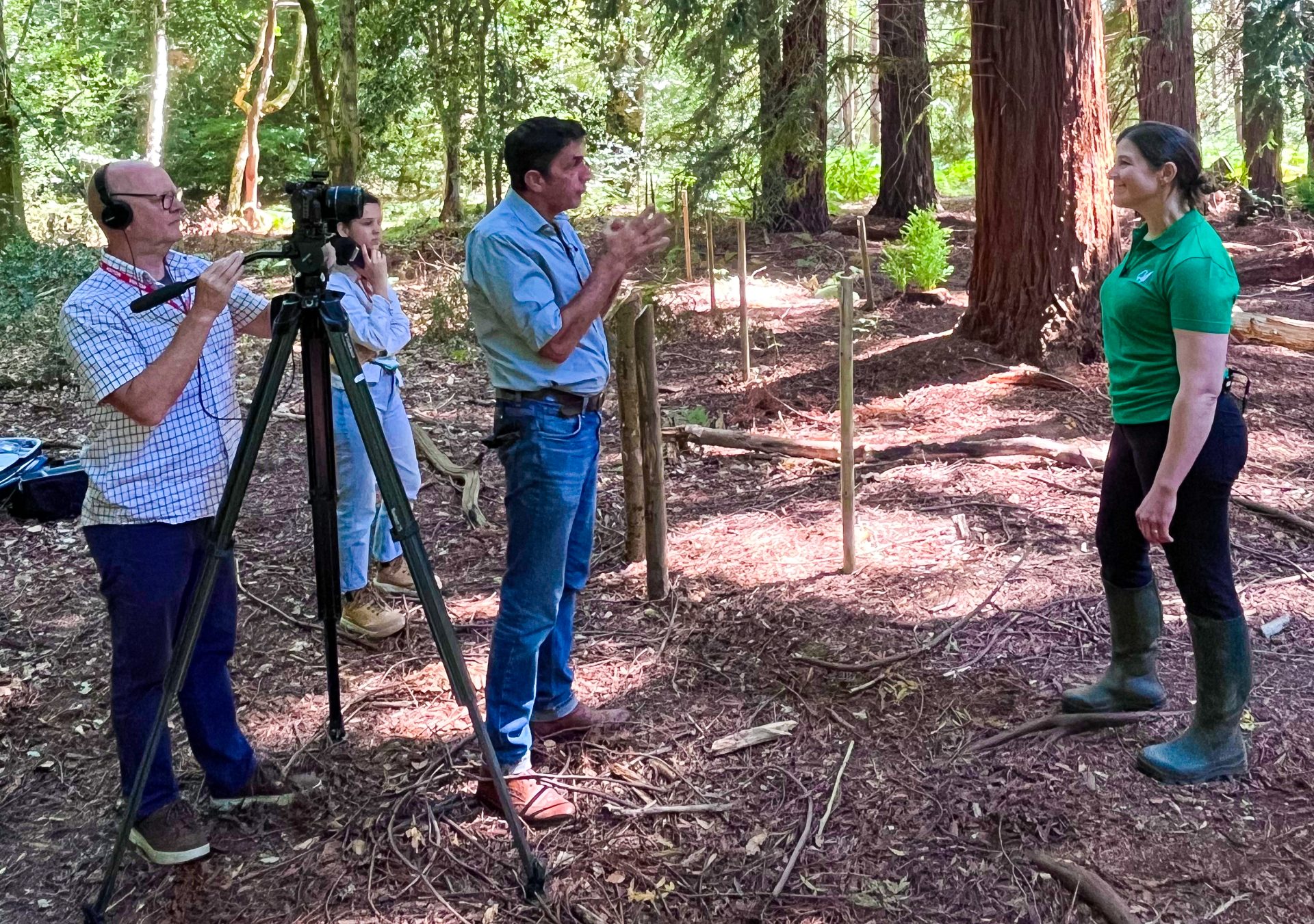 The BBC's Justin Rowlatt interviews Gail Atkinson, Head of Climate Change, standing in a forest with the sun shining through greenery in the background.