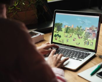 Someone using a PC at a table accessing the new trees outside of woodlands interactive PDF resource