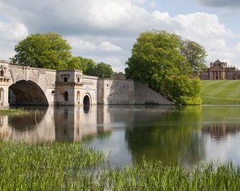 Water and bridge in foreground with Blenheim Palace in distance.