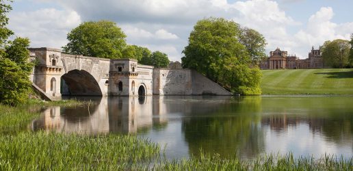 Water and bridge in foreground with Blenheim Palace in distance.