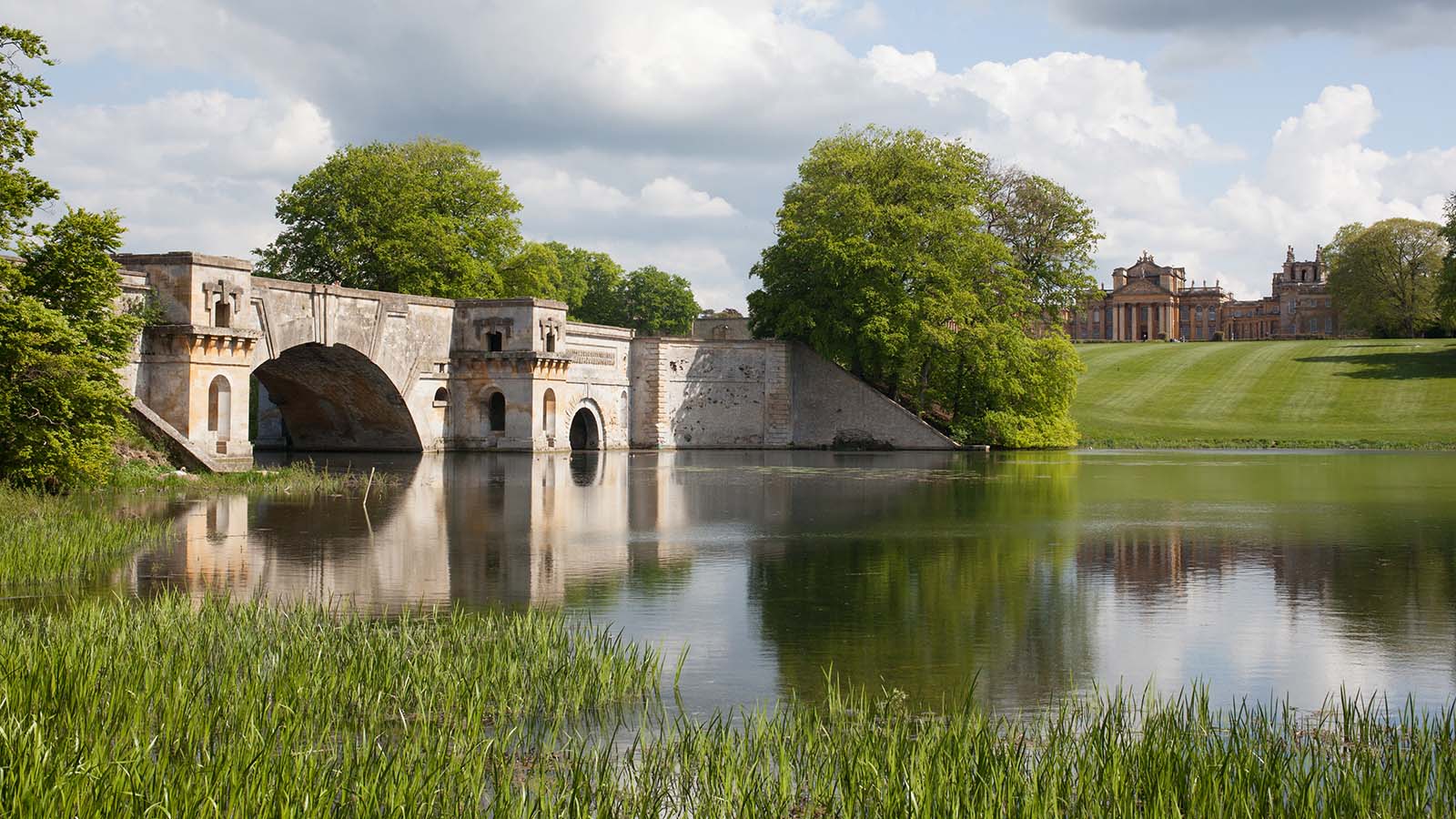 Water and bridge in foreground with Blenheim Palace in distance.