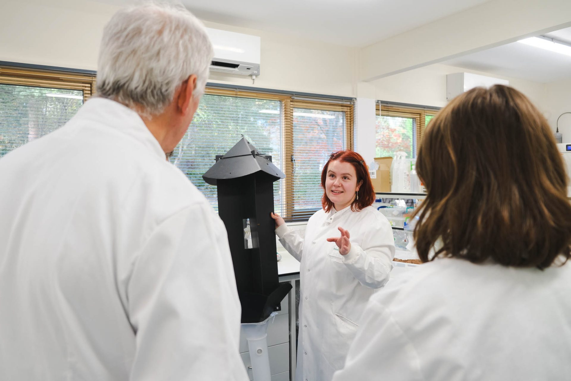 Lab technician holds trap as volunteers look on. 