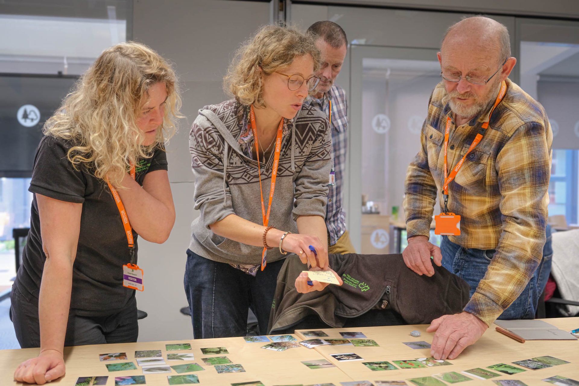 Three people discussing pictures of pests and pathogens laid out on a table.